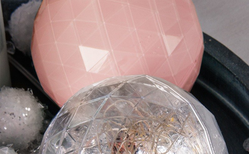 Lachsfarbige und leuchtende Kugel auf Holztablett