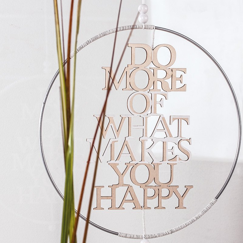 Metallring mit Holzschrift „Do more of what makes you happy“