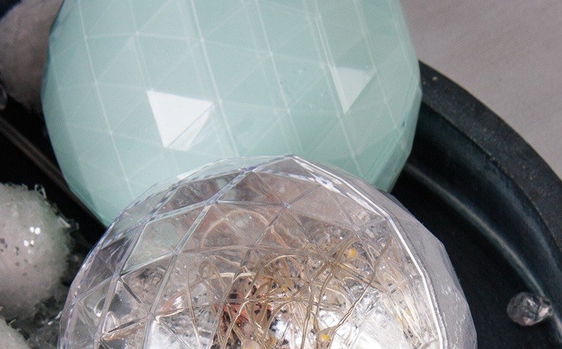 Mintgrüne und leuchtende Kugel auf Holztablett